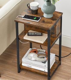 a small wooden table with a phone on top and magazines under it next to a couch