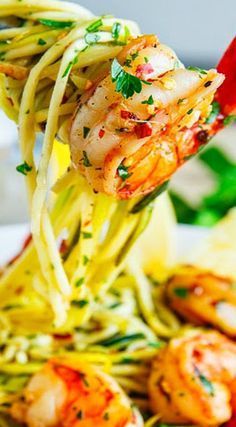 the shrimp is being lifted from the plate with noodles and sauce on it to be eaten