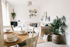 a living room filled with furniture and a wooden table topped with white plates, cups and saucers