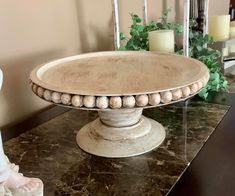 a white cake plate sitting on top of a table next to candles and vases