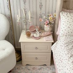 a white dresser with flowers and candles on it next to a bed in a bedroom