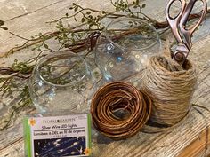 two glass vases with twine wrapped around them on a wooden table next to a pair of scissors