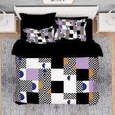 a bed with black and purple comforters, pillows and blankets on top of it