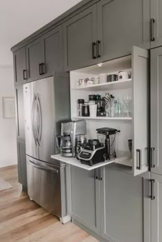 a kitchen with gray cabinets and stainless steel appliances on the counter top, along with an open refrigerator