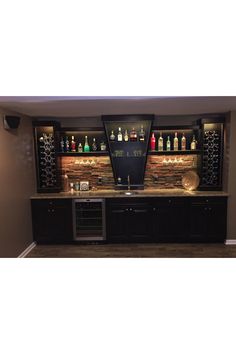 a home bar with wine bottles on the back wall and lights in the front area