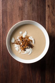 a white bowl filled with soup on top of a wooden table