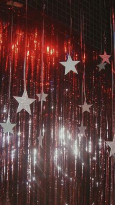 an image of stars hanging from the ceiling with red and white lights behind them on a cell phone screen