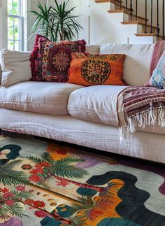 a living room filled with lots of furniture and pillows on top of a rug next to a stair case