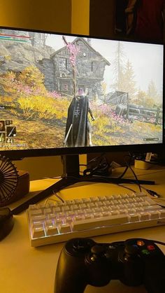 a computer monitor sitting on top of a desk next to a keyboard and game controller