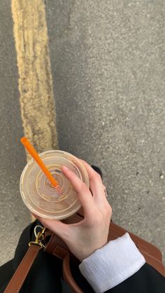 a person holding a plastic cup with an orange straw in it