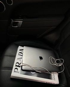 an apple laptop sitting on top of a book in the back seat of a car