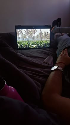 a person laying on a bed in front of a flat screen tv that is turned on