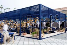 an outdoor dining area with blue and gold decorations on the walls, tables and chairs