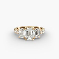 an emerald cut diamond engagement ring with two side stones in yellow gold and white diamonds