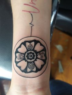 a black and white tattoo on the wrist of a person's arm with a flower design