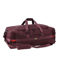 a large duffel bag with straps on the bottom and side pockets, in maroon