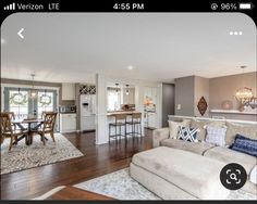 a living room filled with furniture next to a kitchen and dining room table on top of a hard wood floor