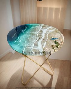 a glass table with gold legs and a blue ocean design on it's top