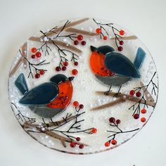 two birds sitting on top of a plate covered in frosting and red berry decorations