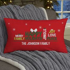 a red christmas pillow sitting on top of a couch next to a window with the words merry