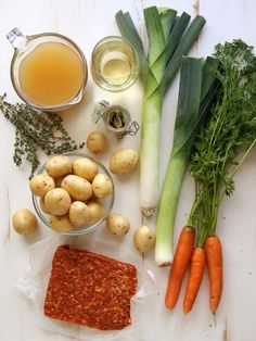 vegetables and other ingredients are laid out on a white surface, including carrots, celery, broccoli, potatoes, and sauce