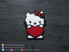 a cross stitch hello kitty holding a heart on a wooden background with the words hello kitty written in german