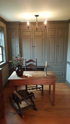 an empty room with a table, chair and vase on the floor in front of it