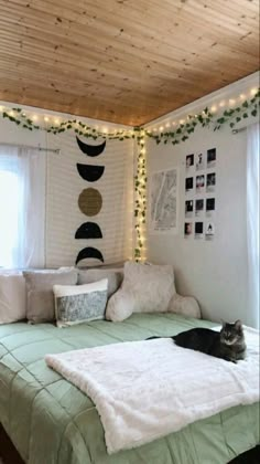 a cat laying on top of a green bed in a room with white sheets and lights