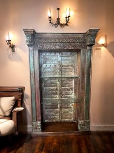 an old wooden door in the corner of a room with two lights on either side