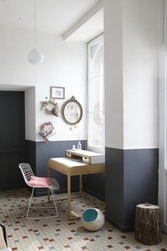 a room with a desk, chair and mirror on the wall next to a window