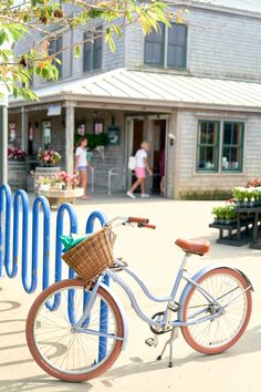 a bicycle is parked in front of a blue fence with people walking by the building