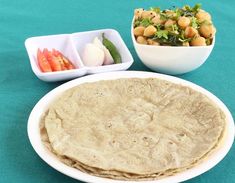 there is a plate of pita bread and two bowls of vegetables on the table