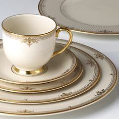 there is a cup and saucer set on the plate with gold trimmings