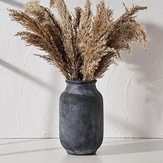 dried grass in a gray vase against a white wall