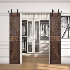 an open wooden door leading into a white room with clothes on hangers and closet doors