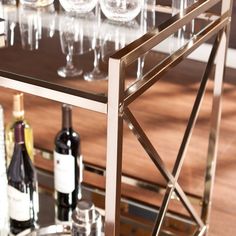 wine glasses and bottles are sitting on a bar cart