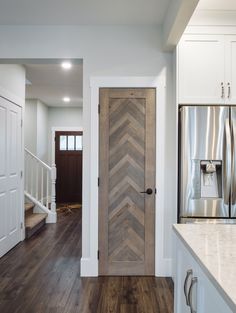 a kitchen with white cabinets and wooden door