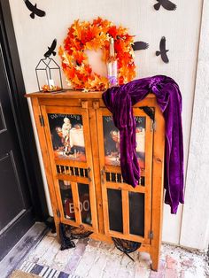 a wooden cabinet with pictures and decorations on it's front door, next to a wreath