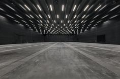 an empty room with lots of lights on the ceiling and concrete floors in front of it