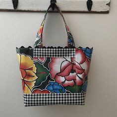 a black and white checkered bag hanging from a hook on a wall with flowers painted on it