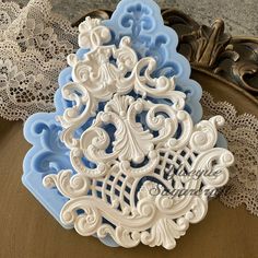 a white and blue cake pan sitting on top of a table next to doily