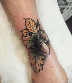 an acorn tattoo on the leg with leaves and acorns