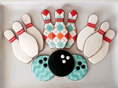 decorated cookies in the shape of bowling pins and skittles on a white tray