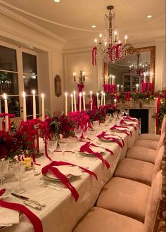 a long table is set with red and white flowers, candles, and place settings