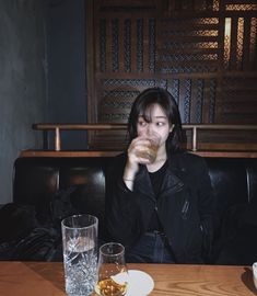 a woman sitting at a table with drinks in front of her and another glass next to her