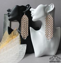 two pairs of earrings are on display next to a white mannequin head and an earring