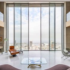 an instagramted photo of a living room with glass walls and floor to ceiling windows