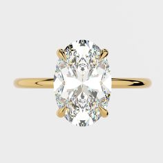 an oval brilliant cut diamond sits in the center of this yellow gold engagement ring, which features four claw prongs