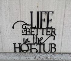 a metal sign that says life is better in the hot tub on a white wall