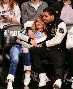 a man and woman sitting next to each other at a basketball game in the stands